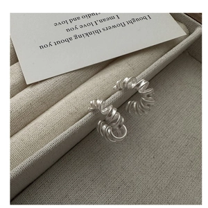 Gros plan de boucles d'oreilles spirales en argent S925 mat sur un socle en velours