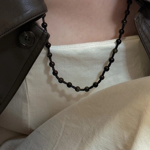 Detail of s925 silver beaded sweater chain with dark natural stones on a model