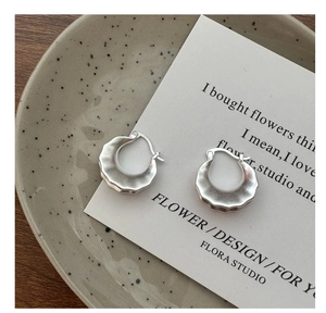 Detail of matte S925 sterling silver hoop earrings with unique wavy edge texture