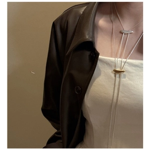 Gros plan de longs colliers minimalistes or et argent superposés sur un mannequin