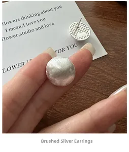Close-up of S925 sterling silver brushed round stud earrings with textured finish