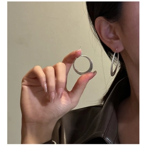 Détail de grandes créoles en argent sterling S925 avec finition mate brossée sur modèle
