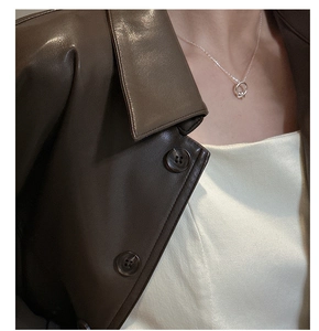 Dettaglio di una collana in argento S925 con nodo minimalista su collo femminile