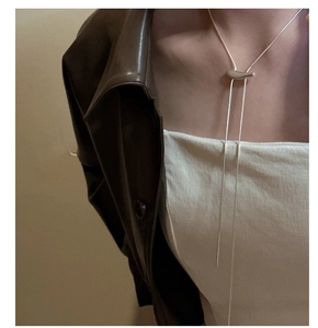 Détail du collier coulissant minimaliste en argent S925 sur une veste en cuir marron