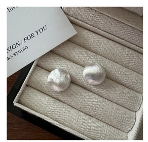 Detail of S925 sterling silver stud earrings with a brushed metal finish in a jewelry box