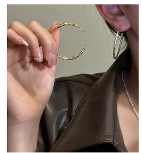 Dettaglio di grandi orecchini a cerchio con superficie martellata irregolare in oro e argento
