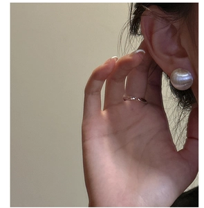 Detail of brushed silver ball earrings and minimalist open ring on a model