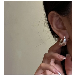 Close-up of matte silver hoop earring with twisted texture worn by a female model