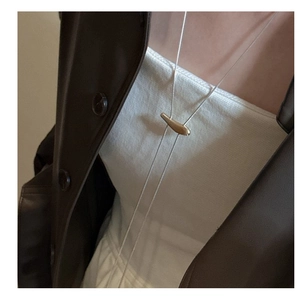 Gros plan d'un collier en argent sterling 925 avec un pendentif haricot doré