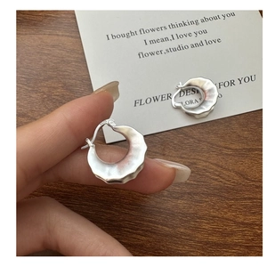 Close-up of S925 sterling silver earring with irregular hammered matte finish texture
