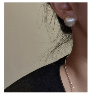 Close-up of minimalist S925 silver round stud earring with brushed matte finish on ear