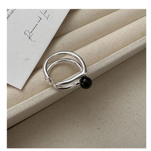 Macro detail of silver double-layered open ring with a black agate bead on pleated fabric
