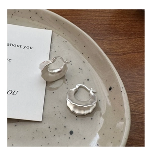 Macro shot of S925 sterling silver hoop earrings with matte texture on ceramic tray
