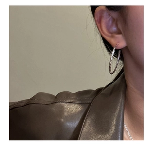 Dettaglio di orecchini a cerchio in argento sterling S925 con finitura martellata su modella