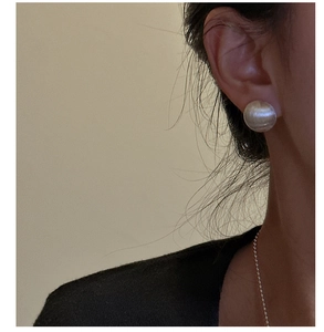 Macro view of minimalist brushed metal stud earring on ear with silver matte finish