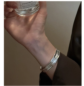Detail of S925 sterling silver cuff bracelet with irregular wavy texture on a female wrist