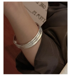Macro detail of silver open cuff bracelet with handcrafted hammered wave texture