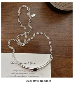 Détail du collier en argent S925 avec barre incurvée et agate noire sur bois sombre