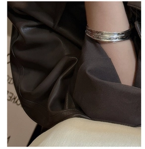 Close-up of S925 sterling silver open bangle with irregular hammered texture on model