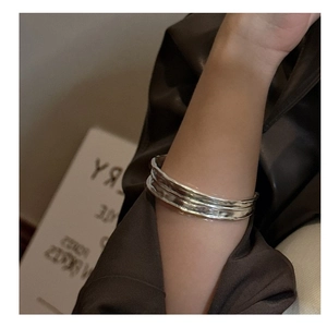 Close-up of a wide minimalist silver bangle featuring hand-crafted irregular texture