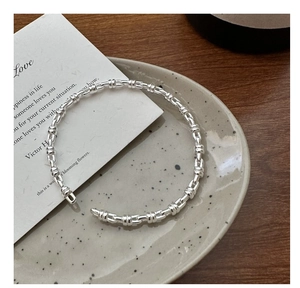 Macro detail of silver adjustable cuff bracelet with segmented bamboo design on ceramic tray