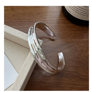 Detailed view of wide S925 sterling silver open bangle with hammered wave texture