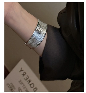 Macro shot of silver wide-band cuff bracelet featuring horizontal textured groove pattern