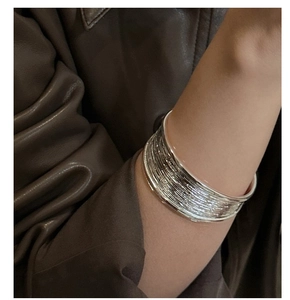 Detailed view of silver cuff bracelet with horizontal brushed texture on a person's wrist
