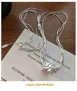 Primo piano della collana a triplo strato in argento con pendente a forma di cubo