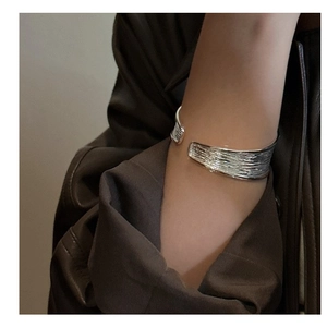 Macro detail of silver cuff bracelet with unique tree bark texture and artistic finish