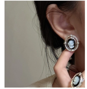 Détail de bagues et boucles d'oreilles camée vintage avec silhouette blanche sur fond noir