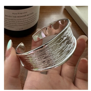 Macro shot of a S925 sterling silver wide open cuff bracelet with detailed brushed texture