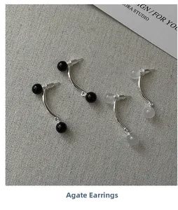 Détail des boucles d'oreilles courbées en argent S925 avec pierres d'agate