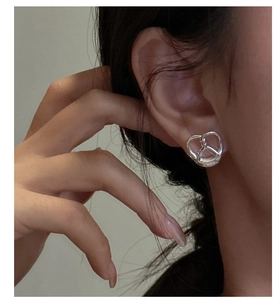 Close-up of a silver knot heart earring worn on ear for minimalist jewelry styling