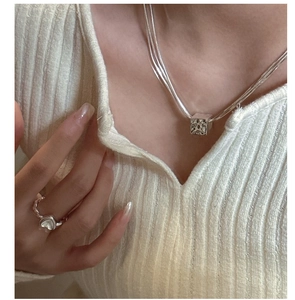 Dettaglio della collana a tre strati in argento con pendente a cubo su una modella