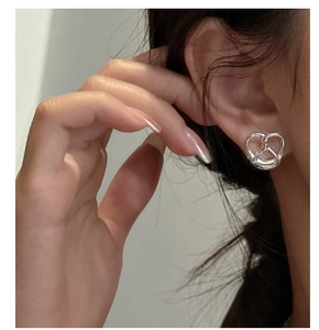 Close-up of S925 sterling silver hollow knot stud earring on model for detailed texture