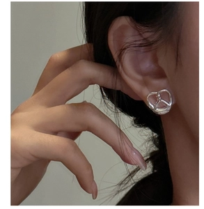 Close-up of S925 sterling silver minimalist pretzel knot stud earring on model ear