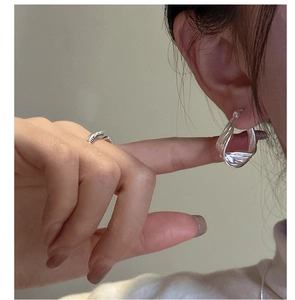 Close-up of textured sterling silver wave hoop earring and matching ring set for women