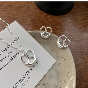 Macro shot of silver pretzel knot necklace and earrings set on a ceramic dish