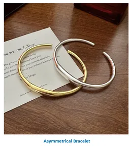 Dettaglio di bracciali irregolari oro e argento esposti su una carta decorativa