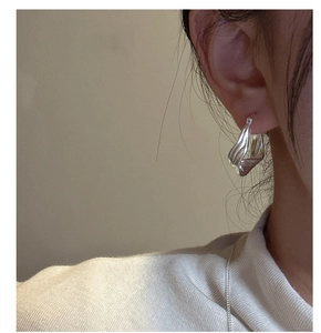 Close-up of S925 sterling silver hoop earrings with twisted wave texture on model