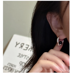 Close-up of minimalist S925 silver C-shape earring with black onyx stone on a model ear