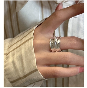 Detailed view of wide silver ring featuring unique irregular pleated texture on hand