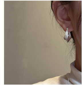 Macro view of S925 sterling silver hoop earrings with irregular textured wave pattern