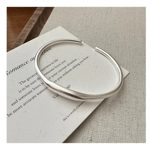 Dettaglio del bracciale aperto in argento opaco dal design organico e moderno