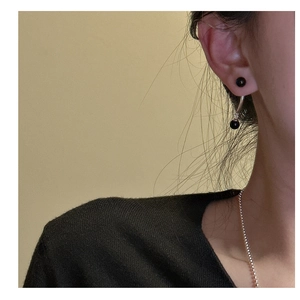 Détail de boucles d'oreilles en argent S925 avec perles d'agate noire portées par un mannequin