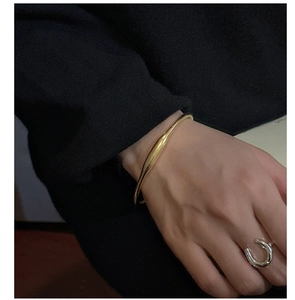 Dettaglio di un bracciale dorato e di un anello d'argento indossati da una modella
