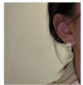 Close-up of a model wearing textured silver hoop earrings with a minimalist matte finish