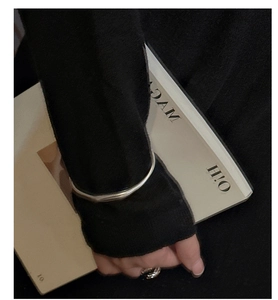 Primo piano del bracciale rigido in argento opaco e dell'anello a treccia sulla modella