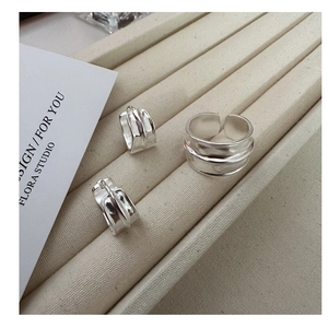 Macro detail of matte silver earrings and ring set with industrial vertical textures